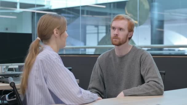 Молодая женщина разговаривает с молодым человеком в офисе — стоковое видео