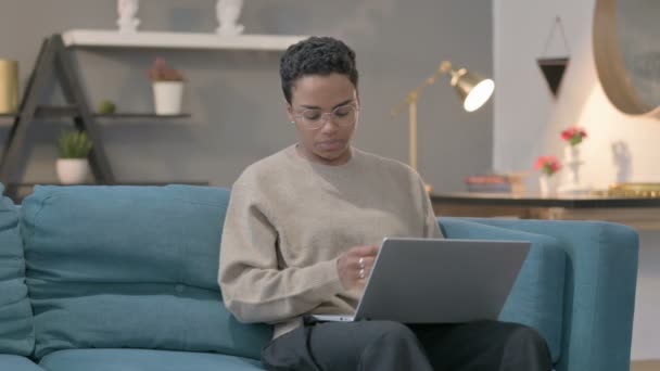 Femme africaine avec ordinateur portable ayant la douleur au poignet sur le canapé — Video