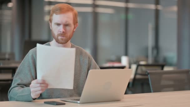 Молодой человек с документами для чтения ноутбуков в офисе — стоковое видео