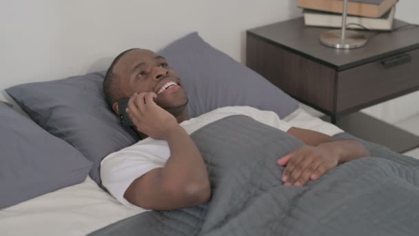 Africano falando em Smartphone enquanto dorme na cama, close-up — Vídeo de Stock