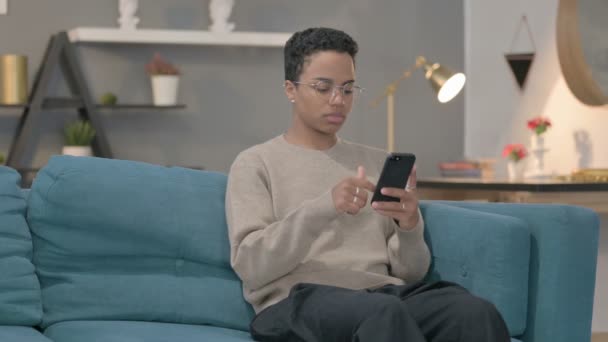 Afrikaanse vrouw met behulp van smartphone op de bank — Stockvideo