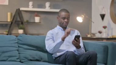 Çekici Afrikalı Adam Kanepe 'de akıllı telefon kullanıyor 