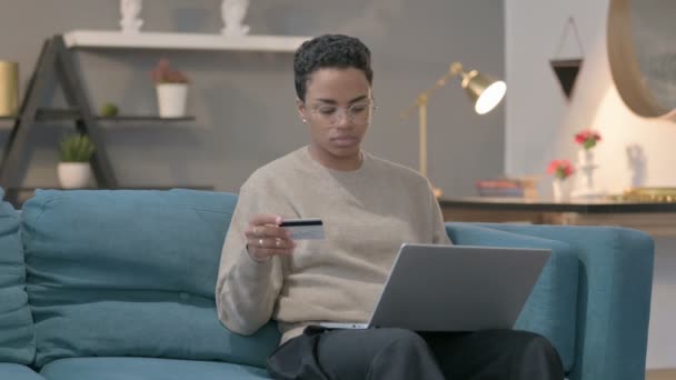 African Woman dokonywania płatności online na laptopie na kanapie — Wideo stockowe