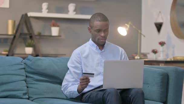 Homem Africano fazendo falha de pagamento on-line no laptop no sofá — Vídeo de Stock