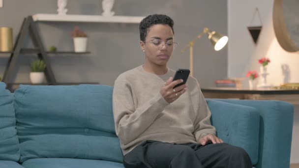 アフリカの女性はソファでスマートフォンで話す — ストック動画