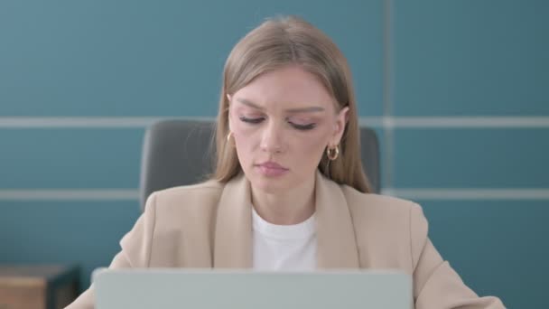 Κοντινό πλάνο του Businesswoman Κοιτάζοντας την κάμερα ενώ χρησιμοποιείτε Laptop στο γραφείο — Αρχείο Βίντεο