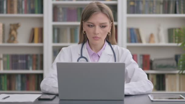 Lady Doctor sonriendo en la cámara mientras usa el ordenador portátil en la clínica — Vídeos de Stock