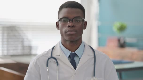 Grave joven africano médico mirando a la cámara — Vídeo de stock