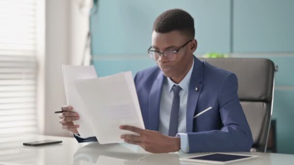 Jóvenes empresarios africanos celebran el éxito mientras leen documentos en el cargo — Vídeos de Stock