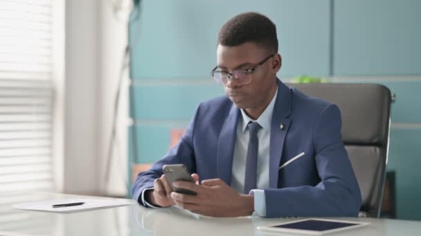 Perturbado joven empresario africano reaccionando a la pérdida en el teléfono inteligente — Vídeos de Stock