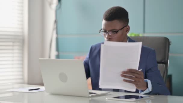 Young African Businessman with Laptop Reading Documents in Office — Stok Video