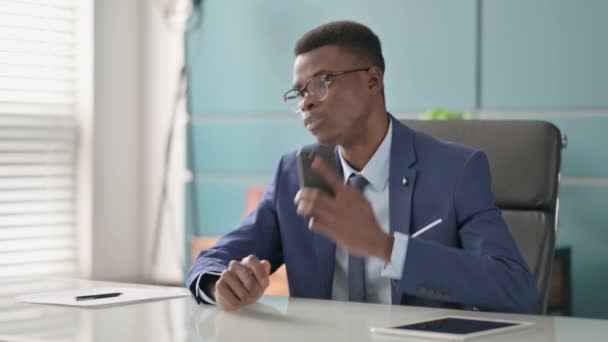 Jonge Afrikaanse zakenman in gesprek over de telefoon in Office — Stockvideo