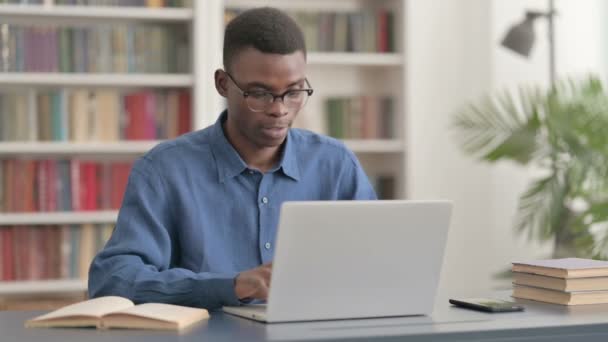 Jonge Afrikaanse man viert succes tijdens het gebruik van laptop in Office — Stockvideo