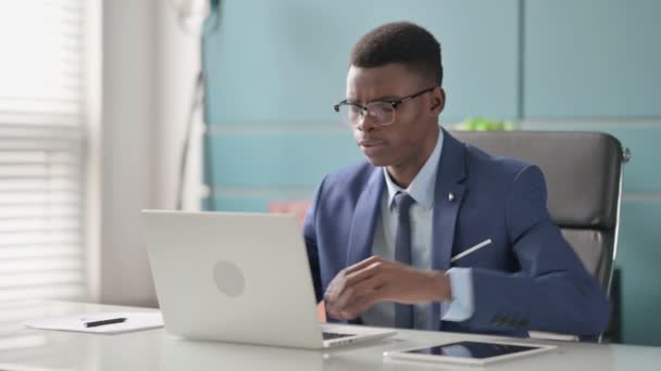 사무실에서 노트북을 사용하면서 등의 통증을 겪고 있는 아프리카의 청년 — 비디오