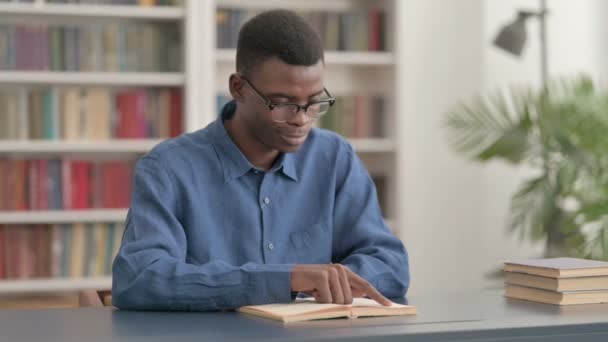 Young African Man Lezen Boek in de Bibliotheek — Stockvideo