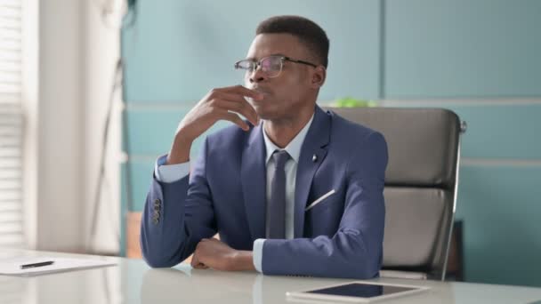 Joven empresario africano pensativo mientras está sentado en el cargo — Vídeos de Stock