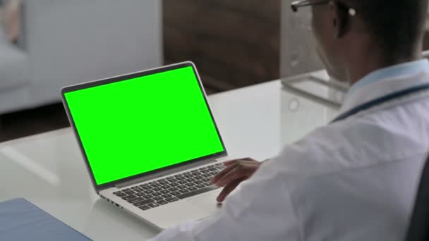 Jonge Afrikaanse arts met behulp van laptop met groen scherm — Stockvideo