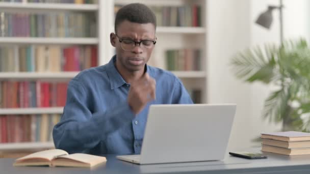 Молодий африканський бізнесмен, який має запальну муку, користуючись ноутбуком у офісі — стокове відео