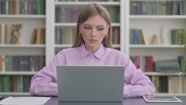 Frau blickt im Büro mit Laptop auf Kamera — Stockvideo