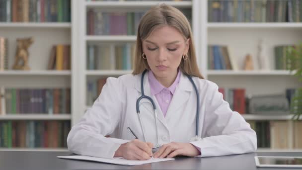 Леди-доктор пишет на бумаге в клинике — стоковое видео