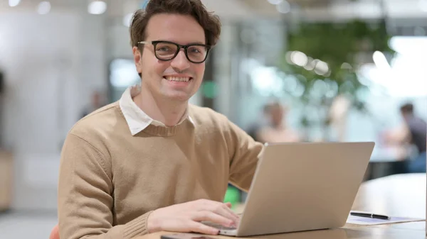 Jeune homme avec ordinateur portable souriant à la caméra — Photo