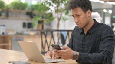 Bilgisayarlı Afrikalı Amerikalı İş yerinde Smartphone kullanıyor