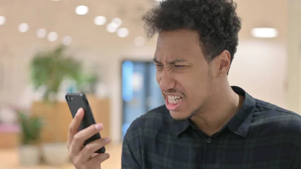 Hombre afroamericano reaccionando a la pérdida en línea en el teléfono inteligente —  Fotos de Stock