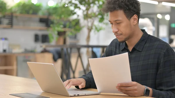 持有笔记本电脑阅读文件的非裔美国人 — 图库照片