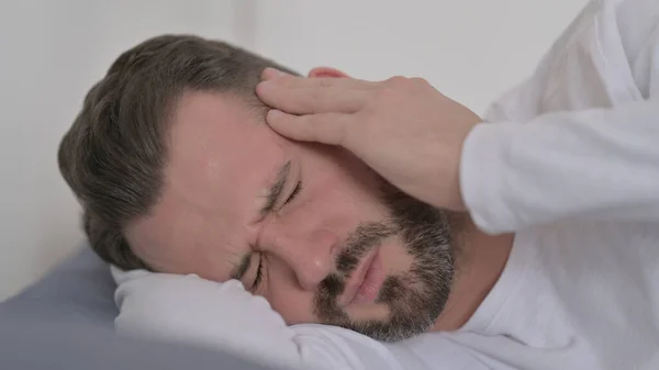 Férfi, akinek fejfájás, miközben alszik az ágyban — Stock Fotó