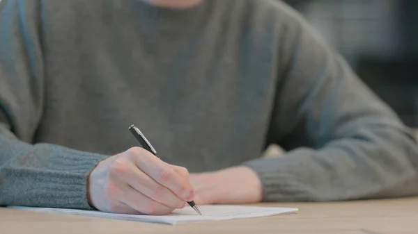 Закрыть руки человека, пишущего на бумаге — стоковое фото