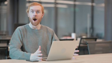 Genç adam ofiste dizüstü bilgisayar kullanırken şok olmuş hissediyor 
