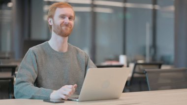 Dizüstü bilgisayarlı genç adam evet işareti olarak başını sallıyor. 