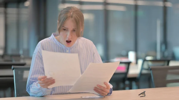 Mladá žena rozrušená při čtení dokumentů v kanceláři — Stock fotografie