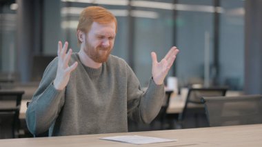 Ofiste otururken üzgün hisseden genç adam.