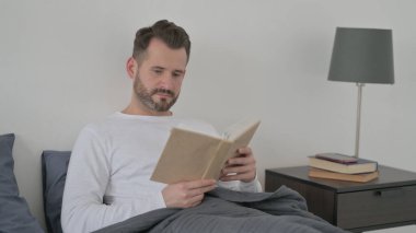 Yatakta Otururken Kitap Okuyan Adam