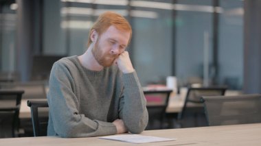 Uykulu genç adam ofiste otururken kestiriyor.