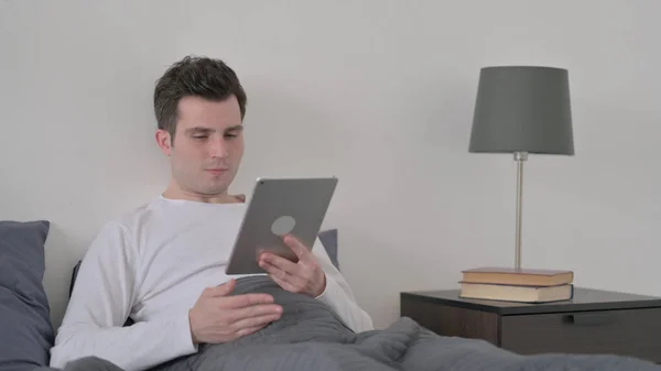 Férfi csinál Video Call a Tablet, miközben ül az ágyban — Stock Fotó