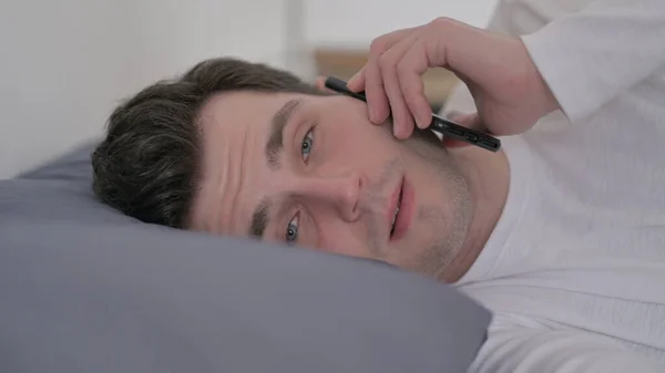 Homem falando ao telefone enquanto dormia na cama, Fechar — Fotografia de Stock
