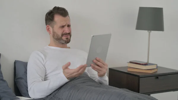 Mężczyzna reaguje na utratę na tabletkę w łóżku — Zdjęcie stockowe