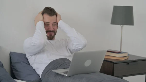 Homem comemorando o sucesso no laptop na cama — Fotografia de Stock