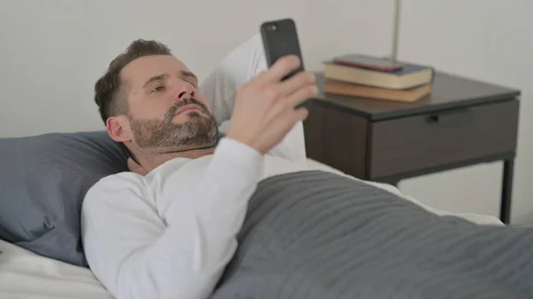 Man using Smartphone in Bed — Stock Photo, Image