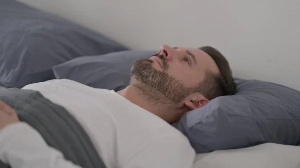 Människan vaknar i sängen tänker — Stockfoto