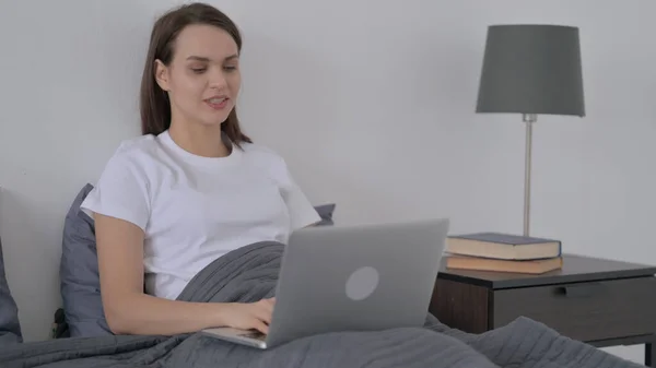 Vrouw doet Video Call op laptop in bed — Stockfoto