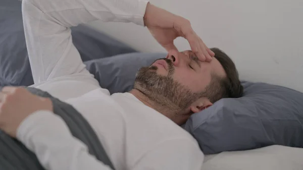 Mann hat Kopfschmerzen beim Schlafen im Bett — Stockfoto