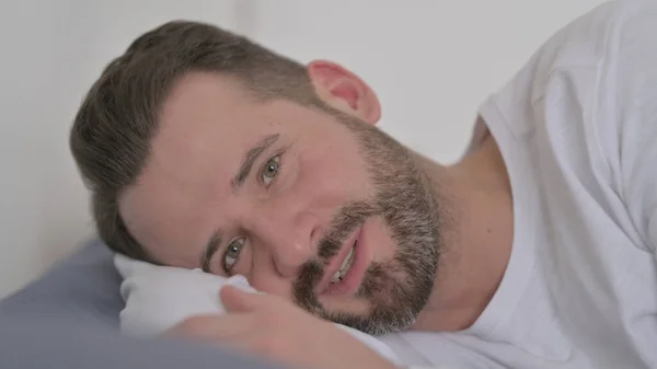 Мужчина разговаривает по видеосвязи, лежа в кровати — стоковое фото