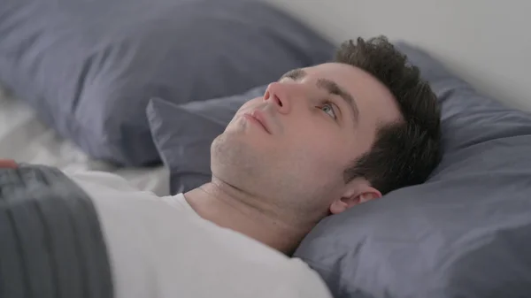 Un bărbat îngrijorat se trezește în pat gândindu-se, de aproape — Fotografie, imagine de stoc