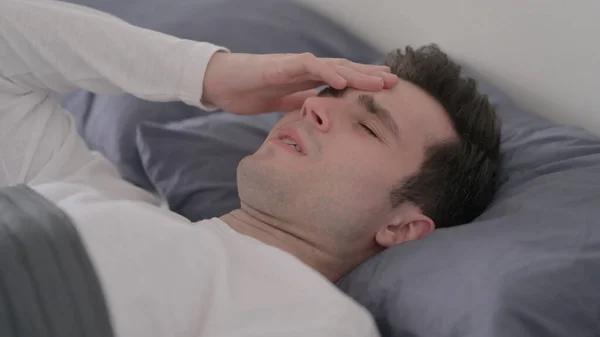 Mann hat Kopfschmerzen während er im Bett schläft, Nahaufnahme — Stockfoto