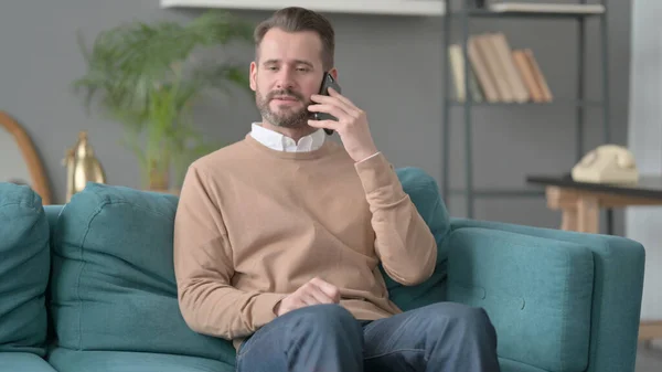Ember beszél telefonon a kanapé — Stock Fotó