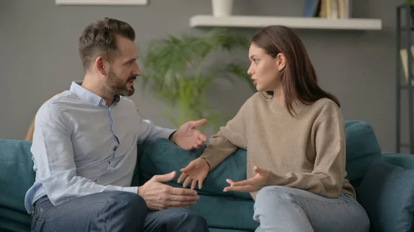 Mulher séria conversando com o homem enquanto sentado no sofá — Fotografia de Stock