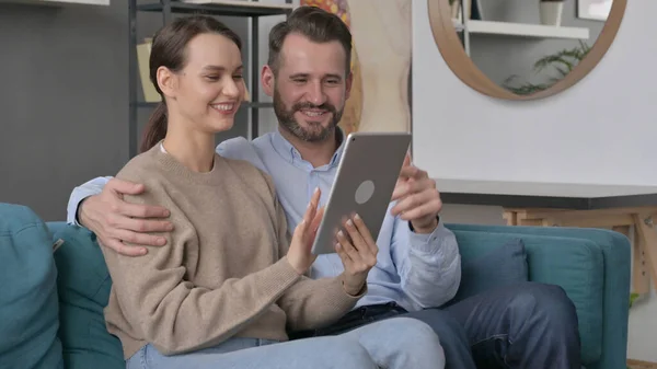 Casal usando Tablet enquanto sentado no sofá — Fotografia de Stock